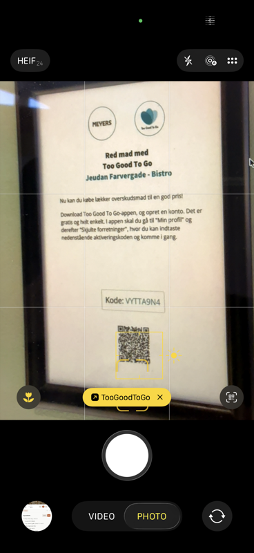 iPhone camera scanning the QR code on the poster